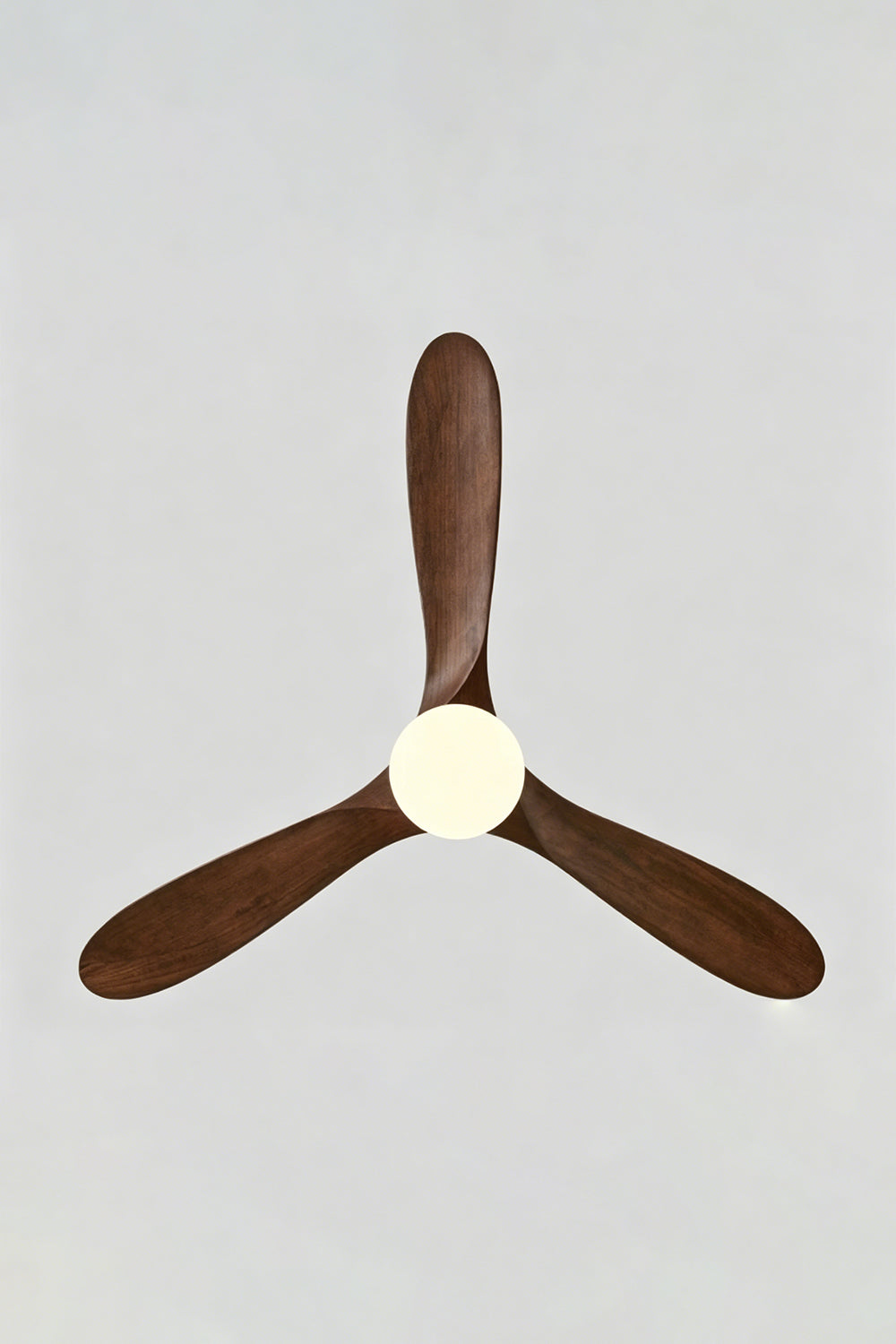 Volant Sculptural Wood Ceiling Fan Light | Wood, Metal | Direct bottom-up perspective showing the symmetrical propeller layout of the three dark walnut wood blades and lit LED disc center | Detail shot | Samu Lamp