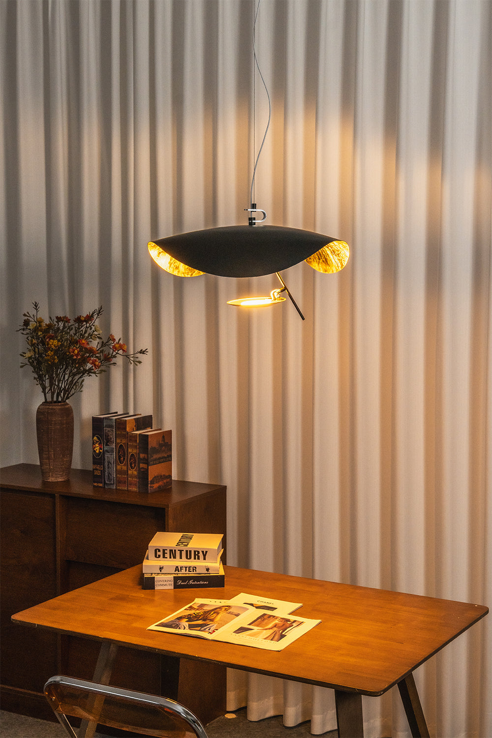 Voluta Horizon Metal Pendant Light | Metal | Fully lit black pendant casting a warm golden glow onto vertical blinds over a wooden table | Samu Lamp