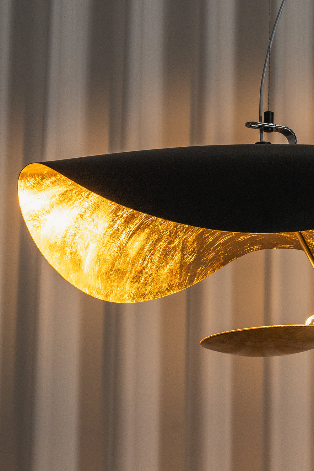 Voluta Horizon Metal Pendant Light | Metal | Close-up profile view of the black outer shell and the radiant textured gold foil inner lining | Detail shot | Samu Lamp