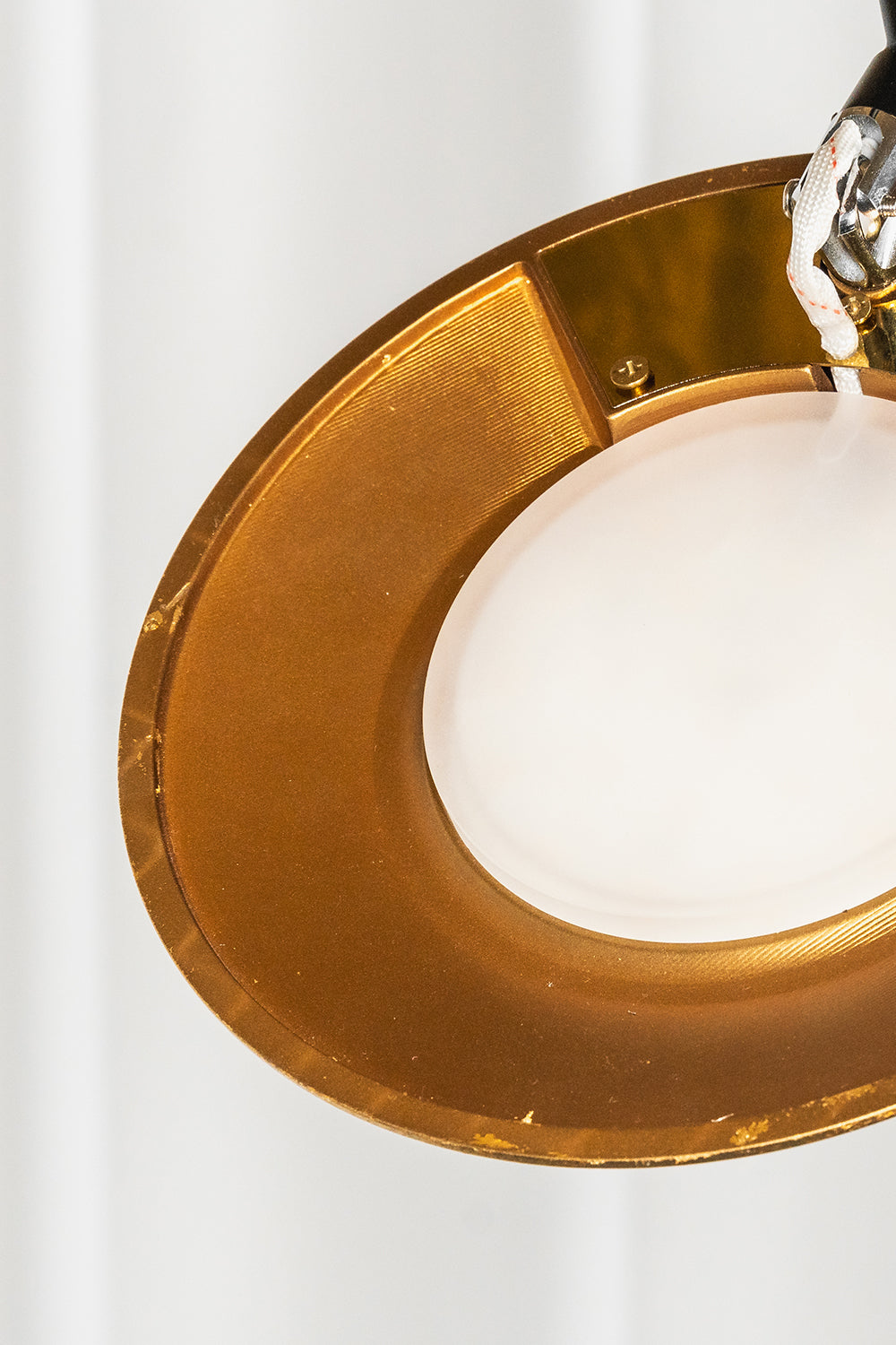 Voluta Horizon Metal Pendant Light | Metal | Close-up of the glowing circular white diffuser set within a polished gold metal ring | Detail shot | Samu Lamp