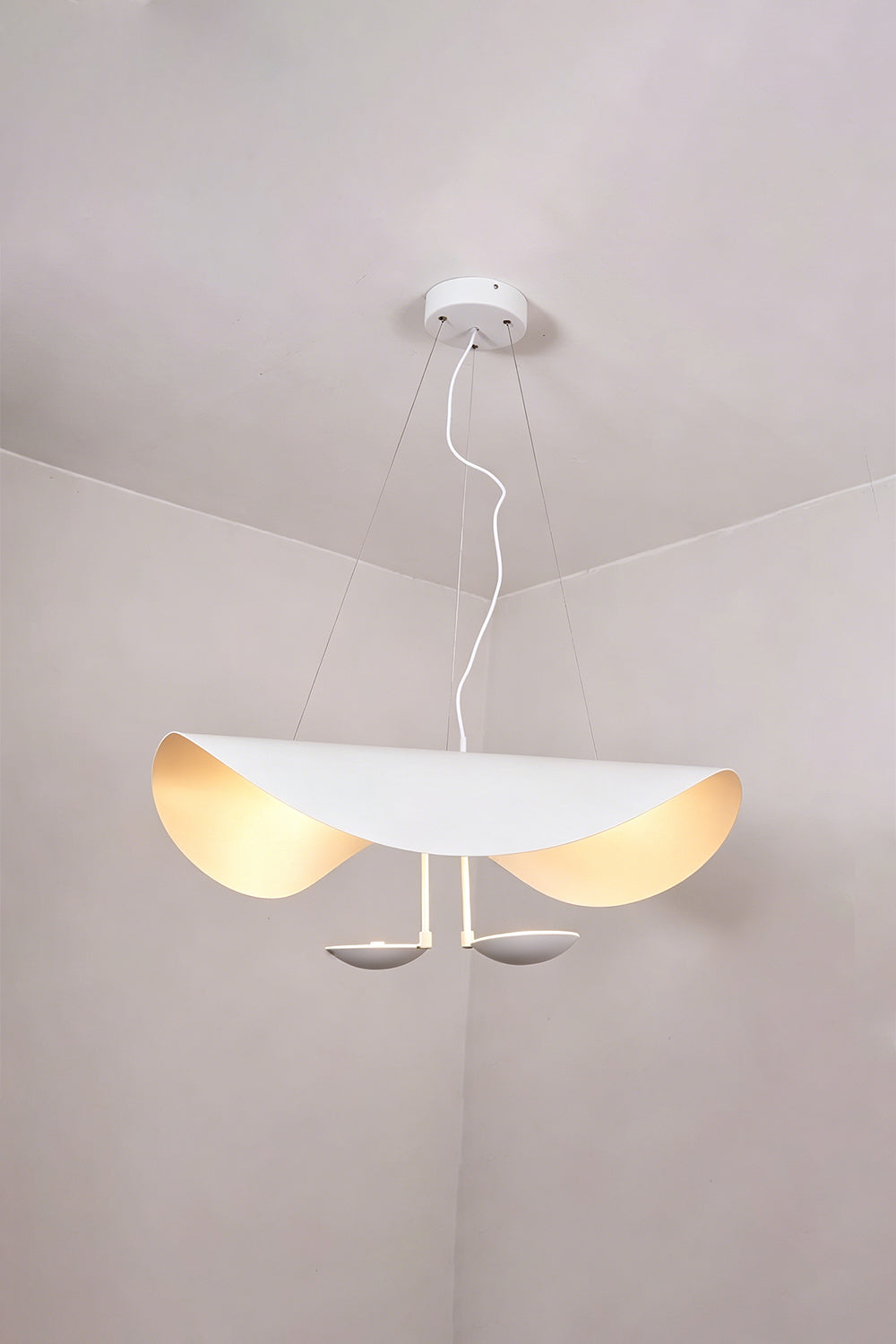 Voluta Horizon Metal Pendant Light | Metal | White variant hanging and glowing warmly in a minimalist room corner | Samu Lamp