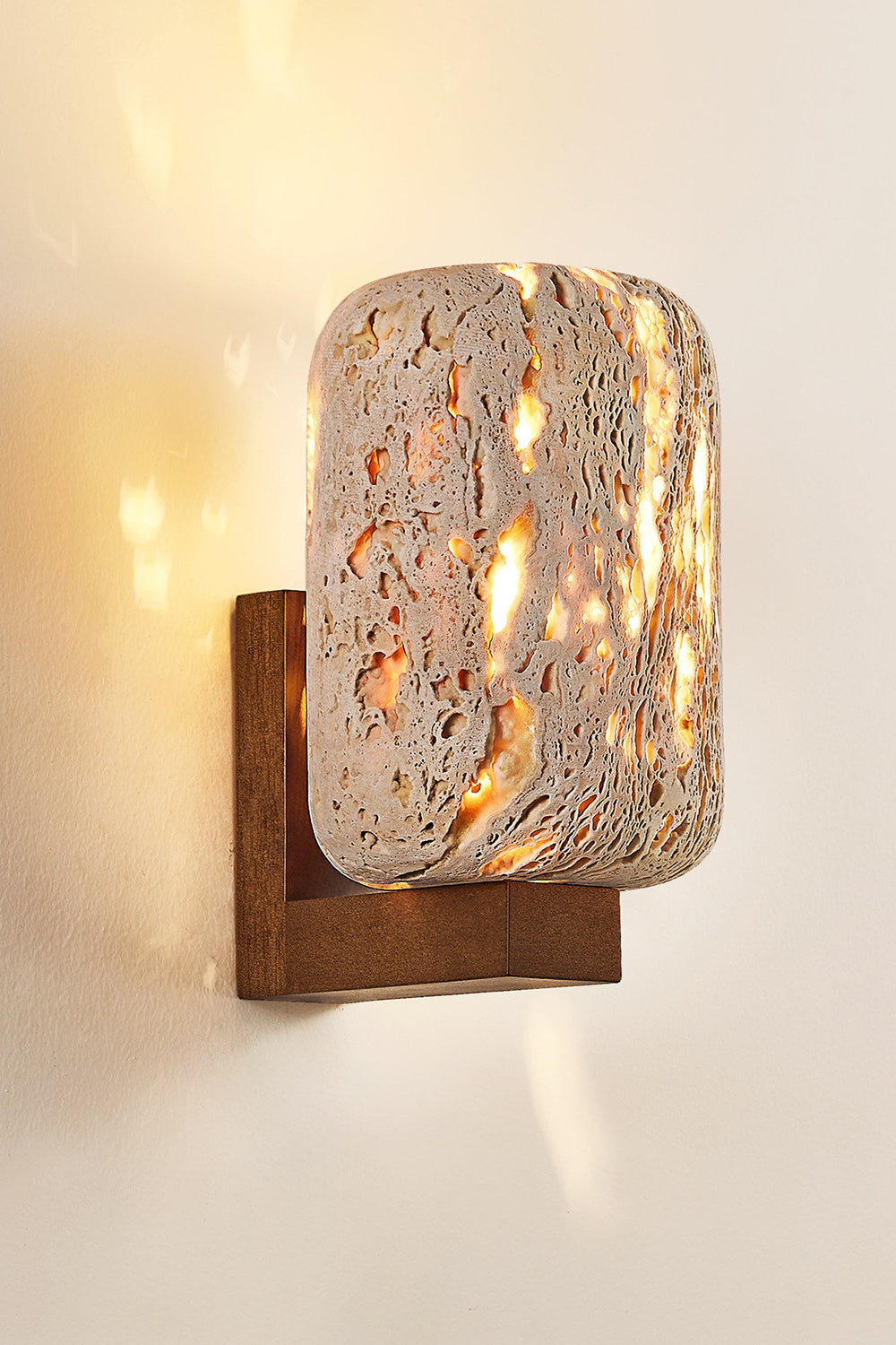 Close-up of lit Wabi-Sabi travertine wall lamp | Travertine, Wood | Showing the porous stone texture and wooden bracket | Samu Lamp