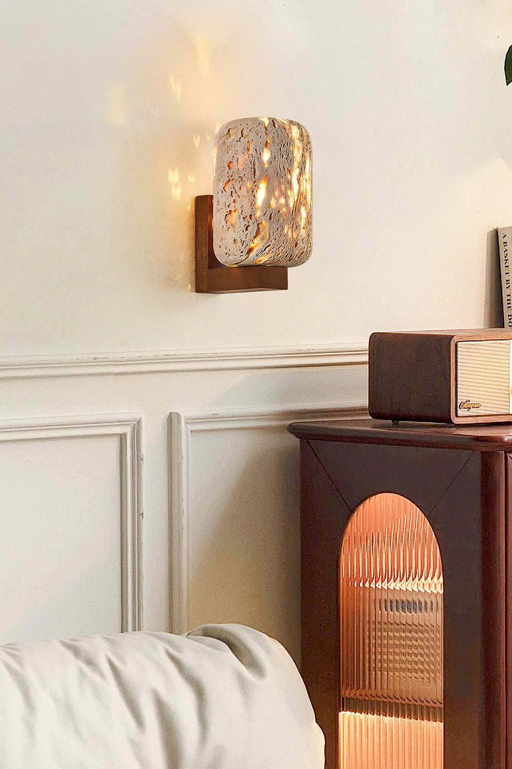 Wabi-Sabi stone wall light on a classic molded wall | Travertine, Wood | Interior scene near a dark wooden side table | Samu Lamp