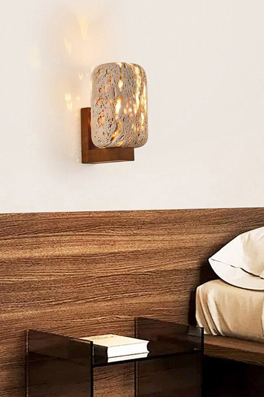 Travertine cylinder sconce providing warm glow | Travertine, Wood | Mounted above a wooden headboard in a minimalist bedroom | Samu Lamp