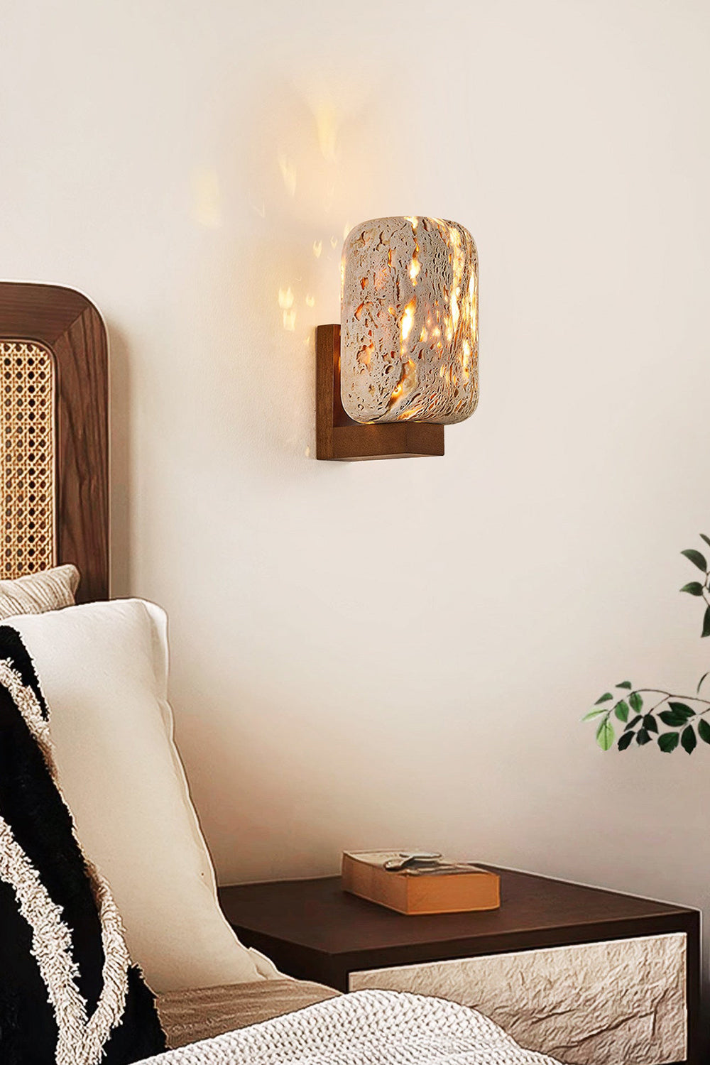 Lit cylinder stone wall sconce | Travertine, Wood | Positioned next to a rattan bed and dark nightstand | Samu Lamp