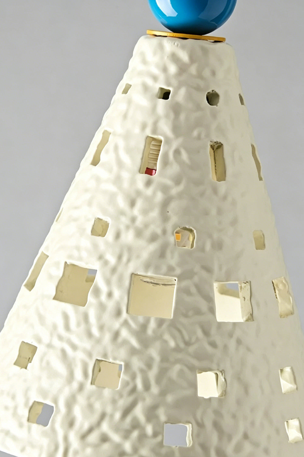 Carousel Horizon Ceramic Wall Sconce | Metal, Resin, Ceramics | Frontal view of the fully lit sconce against a plain wall, showing light filtering through the perforated shade | Isolated shot | Samu Lamp