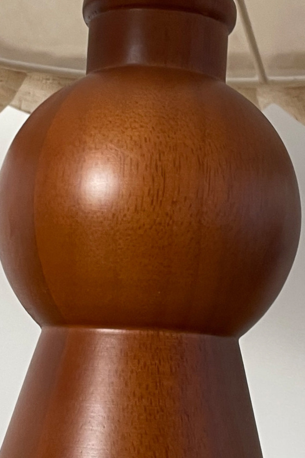 Whiskers Ruffled Fabric Table Lamp | Fabric, Wood | Close-up focus on the smooth curves and polished rich grain of the sculpted warm brown wood lamp base | Detail shot | Samu Lamp