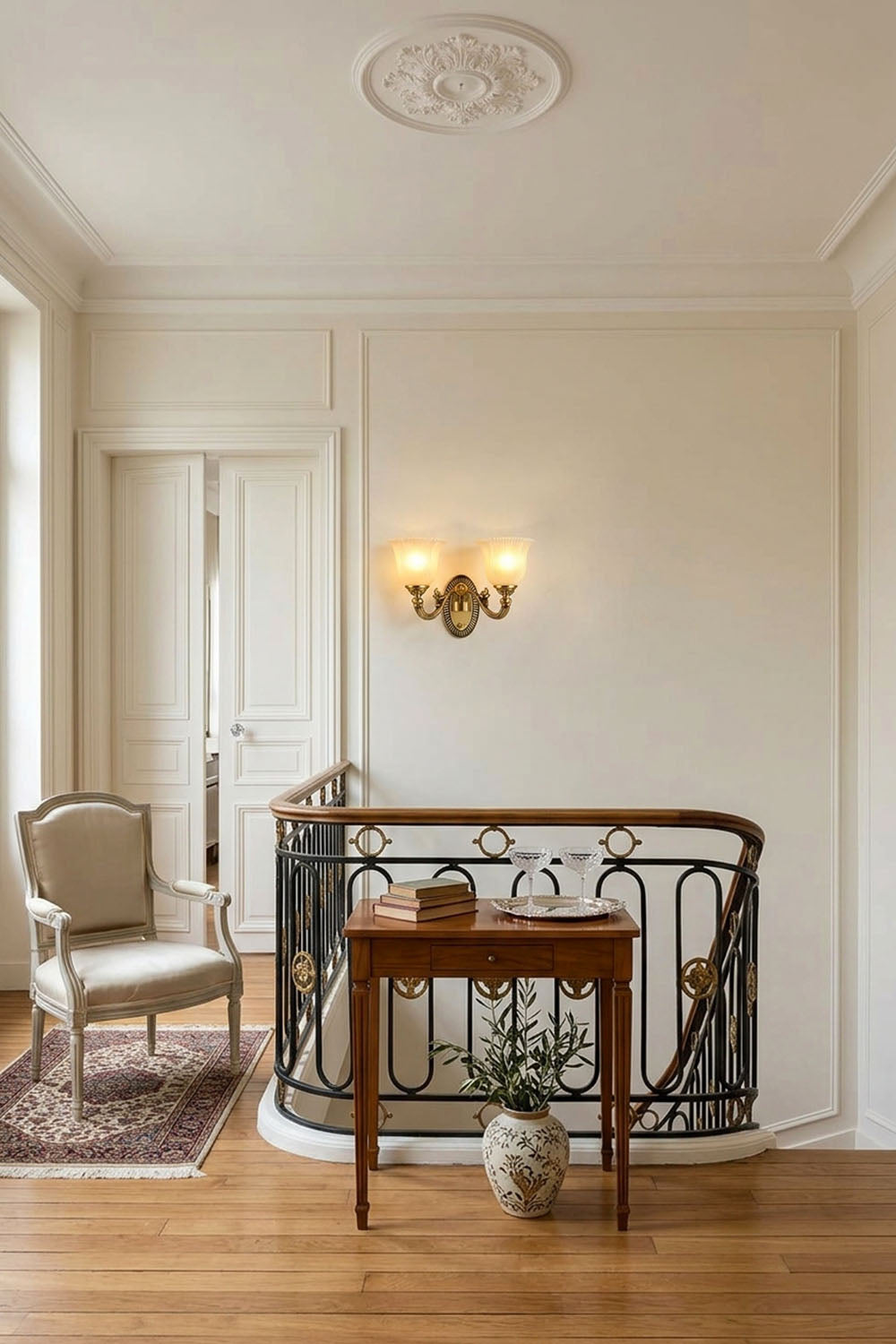 Interior view showcasing a staircase with a Whitlock Fluted Bell Brass Wall Lamp illuminating a stylish chair and table.