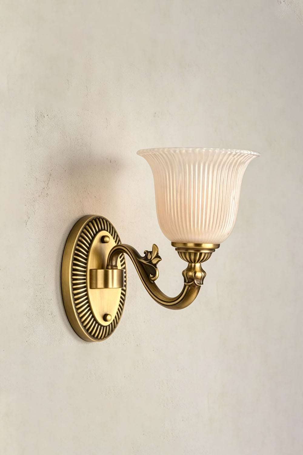 Whitlock Fluted Bell Brass Wall Lamp mounted on a wall with a fluted glass shade and ornate brass arm.