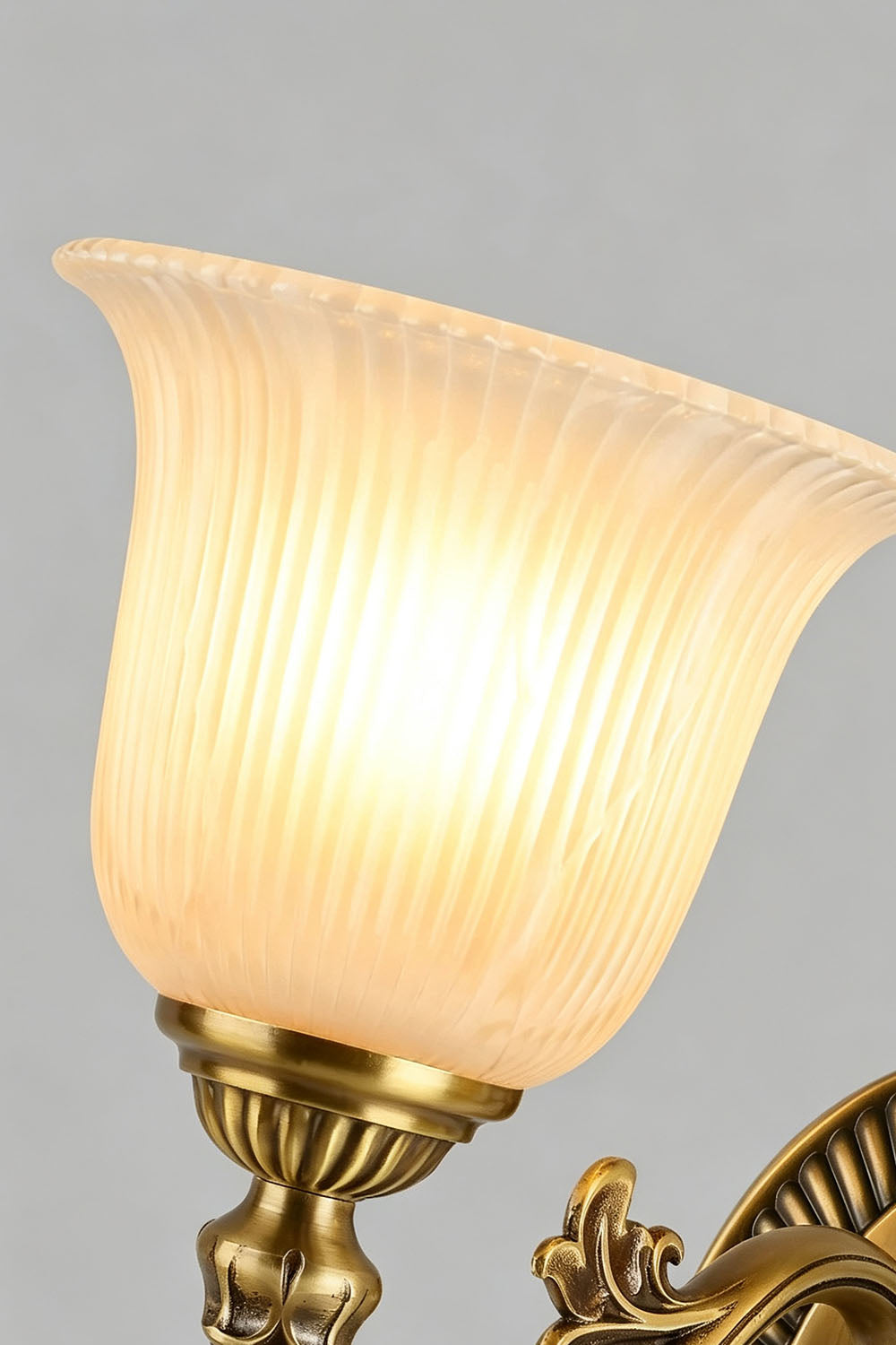 Close-up of the Whitlock Fluted Bell Brass Wall Lamp showcasing its elegant fluted glass shade illuminated.