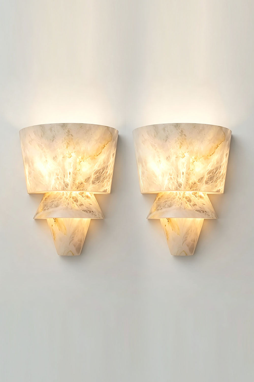 Wystan Twin Cone Alabaster Wall Lamp | Natural Alabaster and Metal | Pair of sconces mounted side-by-side on a plain wall, illuminated | Samu Lamp