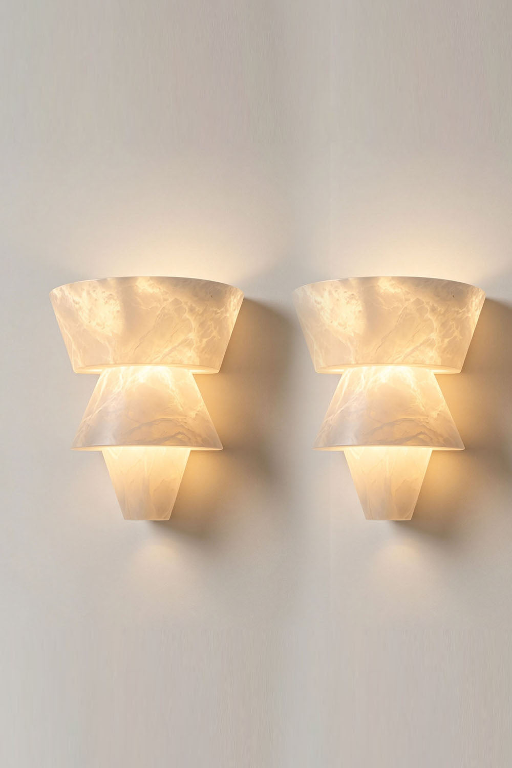 Wystan Twin Cone Alabaster Wall Lamp | Natural Alabaster and Metal | Pair of sconces glowing warmly side-by-side on a neutral backdrop | Samu Lamp