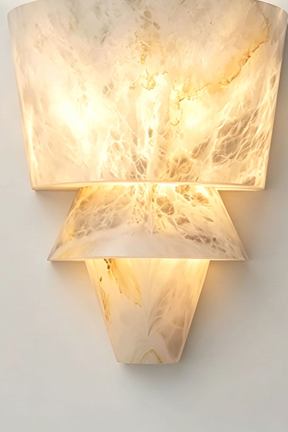 Wystan Twin Cone Alabaster Wall Lamp | Natural Alabaster and Metal | Close-up view highlighting the glowing carved alabaster texture and tiered cone structure | Samu Lamp
