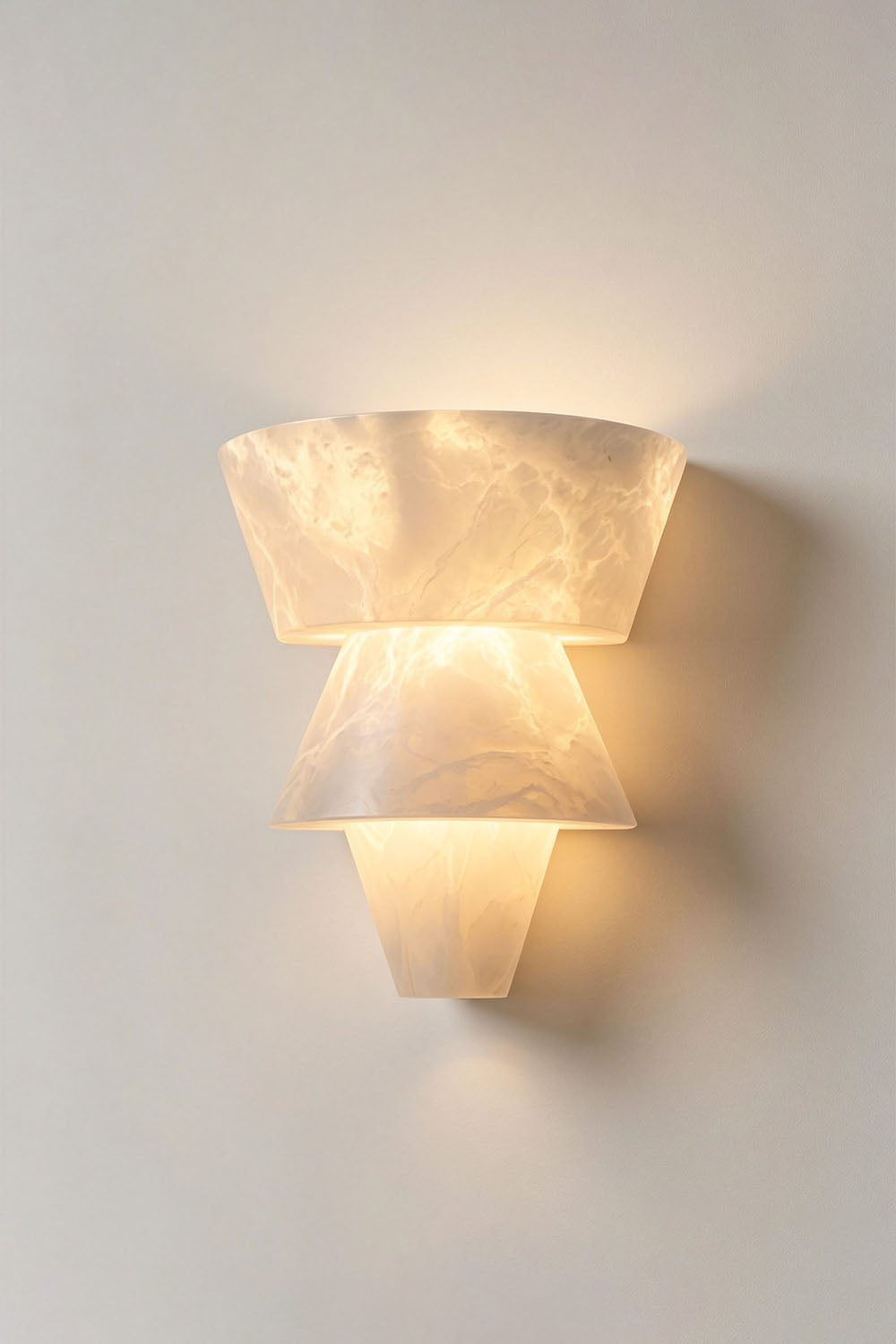 Wystan Twin Cone Alabaster Wall Lamp | Natural Alabaster and Metal | Centered illuminated view of the double cone lamp on a plain backdrop | Samu Lamp