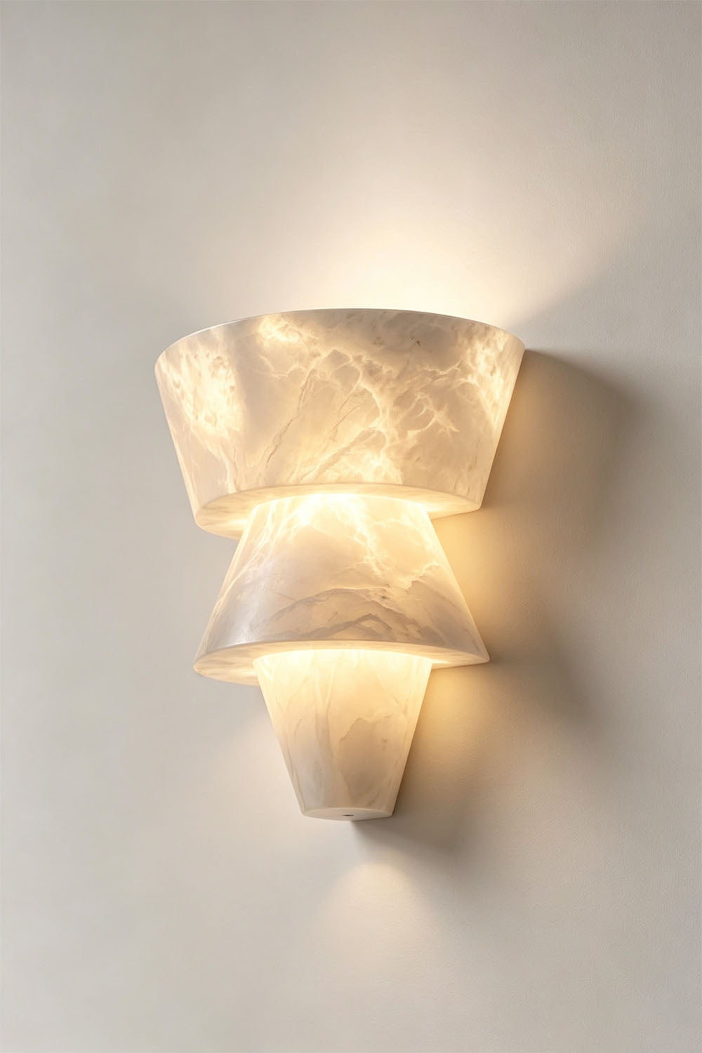 Wystan Twin Cone Alabaster Wall Lamp | Natural Alabaster and Metal | Full product view glowing brightly against a light grey backdrop | Samu Lamp