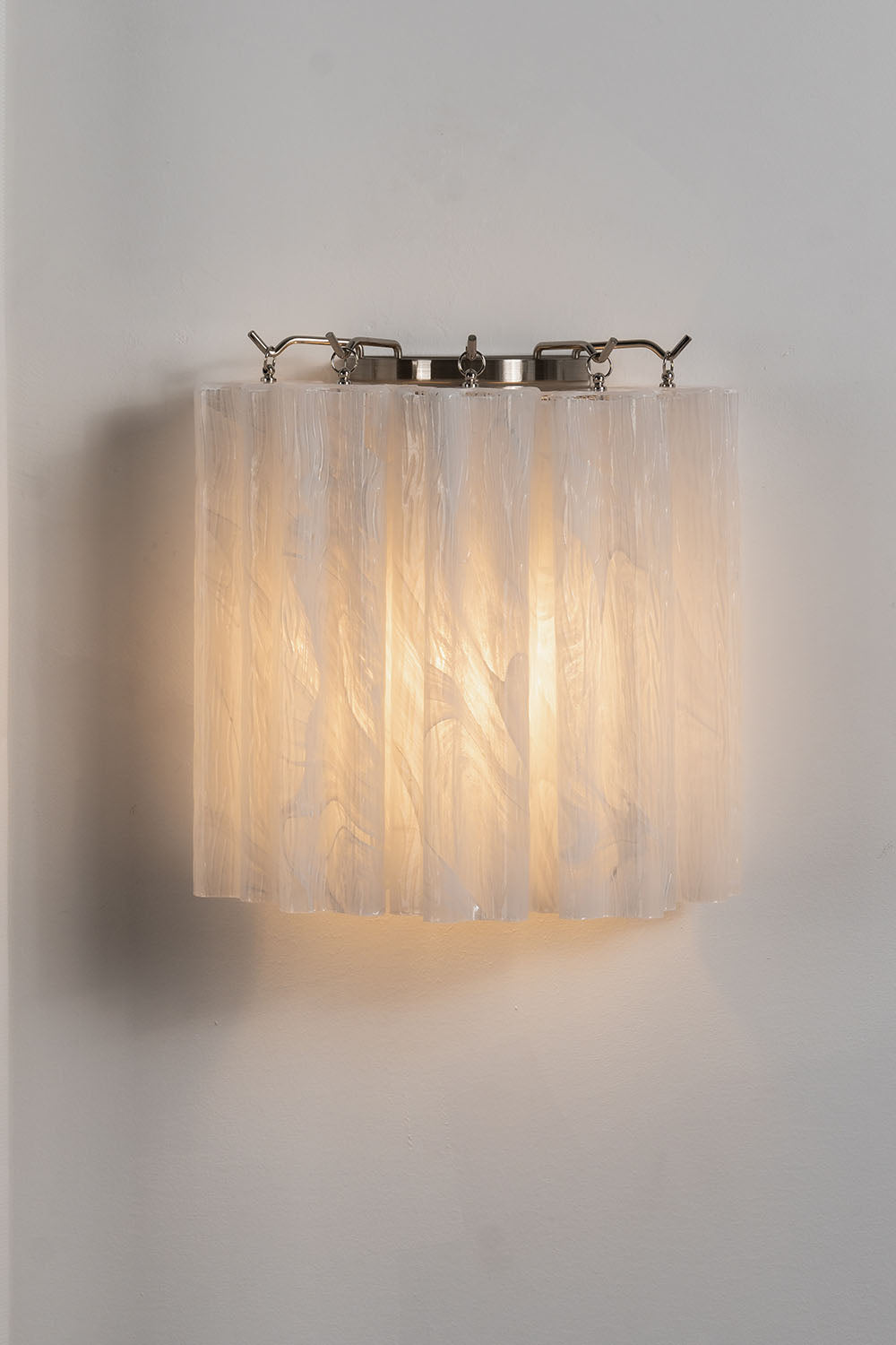 Ysoline Rippled Glass Curtain Sconce Light | Rippled Glass and Metal | Front illuminated view displayed warmly against a plain backdrop | Samu Lamp