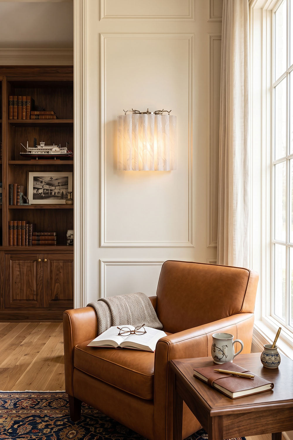 Ysoline Rippled Glass Curtain Sconce Light | Rippled Glass and Metal | Mounted on a wall beside a leather armchair in a reading corner | Samu Lamp